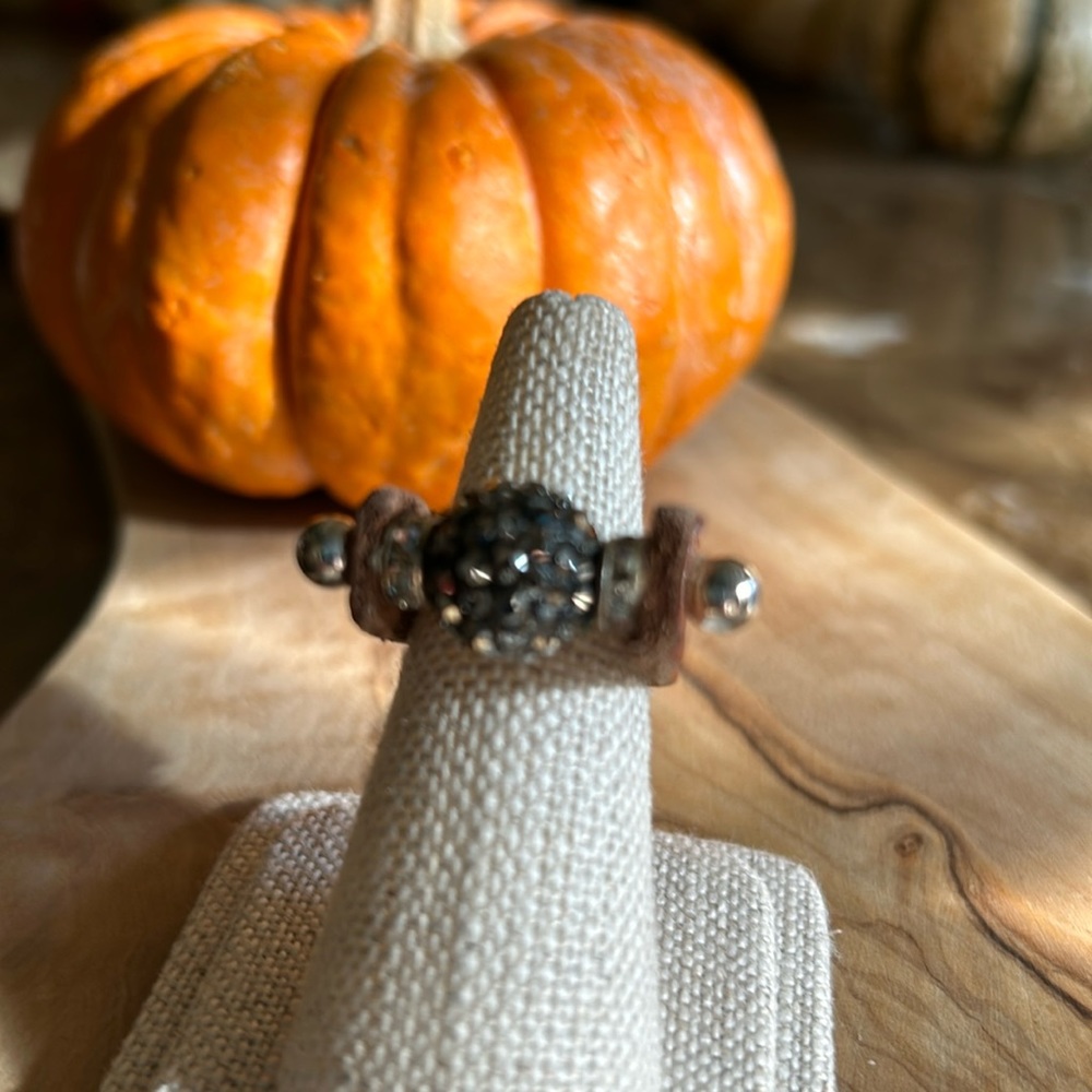 Leather ring w/ball of dark gray center crystals on a sterling silver pin.